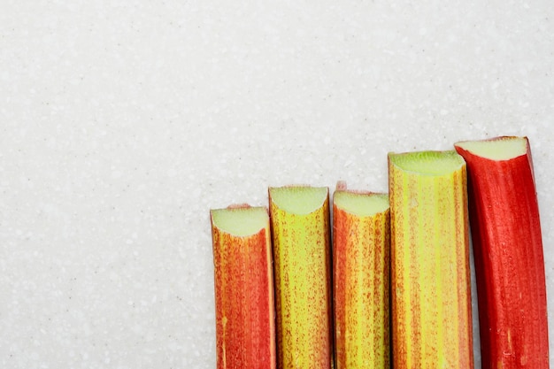 Stems of ripe rhubarb on a white background top view with copy space ingredients for making traditional seasonal pies