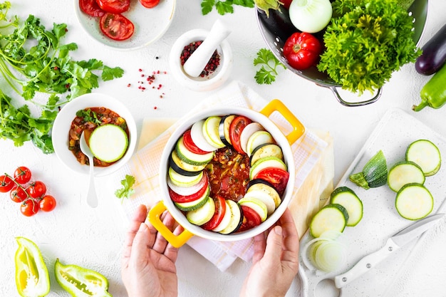 Step 4 Different vegetables A healthy diet Ingredients for baking Vegetable ratatouille on a white background Hands in the frame Top view