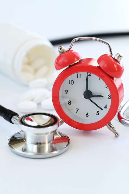 Stethoscope, alarm clock and white pills closeup. Healthcare