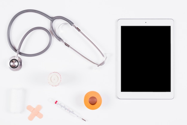 Stethoscope; bandages with thermometer and digital tablet on isolated on white background