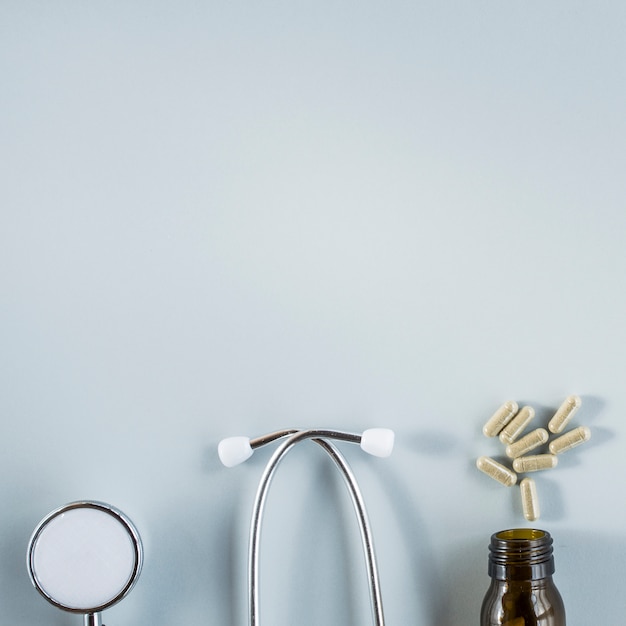 Free photo stethoscope and capsules above the bottle over the grey background