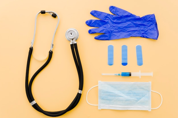 Stethoscope; crumpled gloves; bandages; syringe and surgical gloves on yellow background