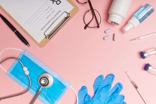 Stethoscope in doctors desk, medical concept. corona virus covid-19. stethoscope, eyeglasses and face mask on pink desk. Protection against virus, coronavirus, flu, colds, diseases. flat lay. top view