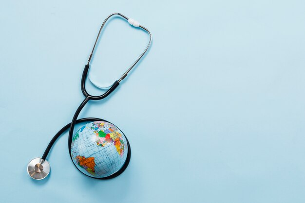 Stethoscope hugging Earth on blue background