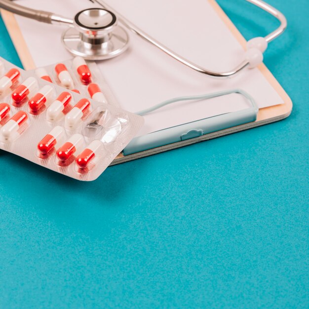 Stethoscope and pills on clipboard