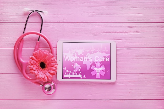 Stethoscope, tablet computer and flower on wooden table. gynecology concept