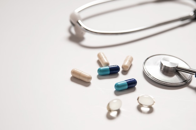 stethoscope on white background with mix pills isolated