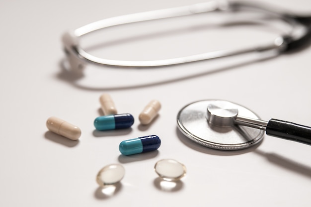 stethoscope on white background with mix pills isolated
