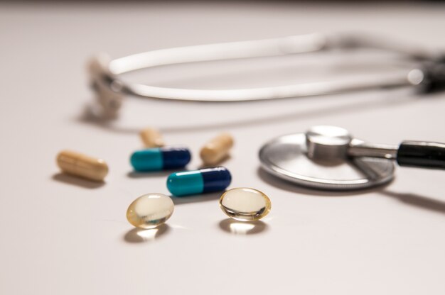 stethoscope on white background with mix pills isolated