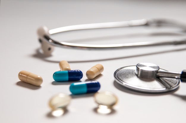 stethoscope on white background with mix pills isolated