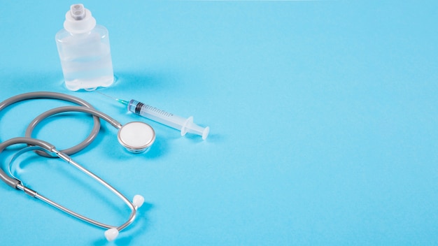 Stethoscope with ampoules and syringe on blue backdrop