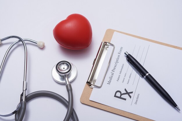 Stethoscope with heart. Stethoscope and red heart on wooden table. Hospital life insurance concept. World heart health day idea. Medicine or pharmacy concept. Empty medical form ready to be used.