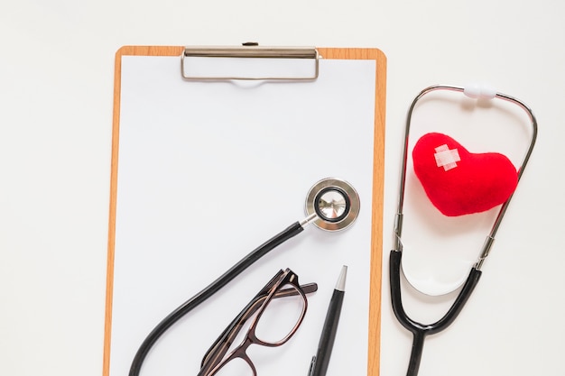 Stethoscope with stuffed red heart with bandage on clipboard