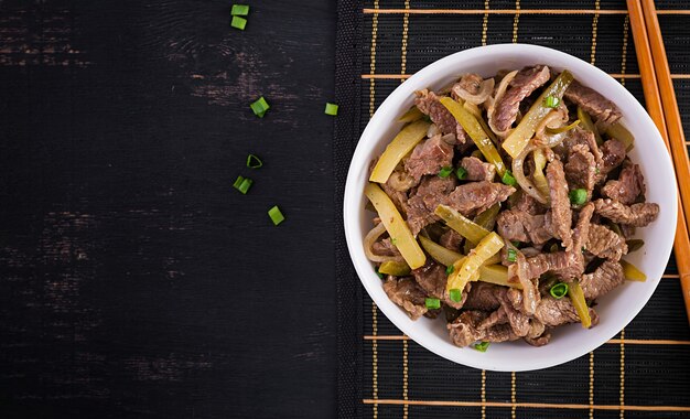 Stew beef, pieces of beef stewed in soy sauce with spices with pickled cucumber in asian style. Top view, overhead, flat lay