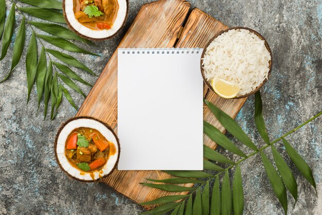 Stew and rice in coconut plates with empty notepad