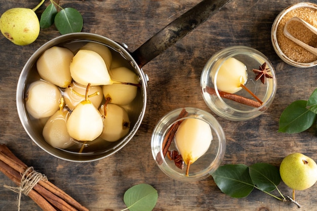 Pere in umido pentola di pere dolci stufate con sciroppo o vino bianco su un tavolo di legno verde il processo di cottura