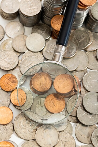 Magnifying glass on a pile of money coins. Stock Photo