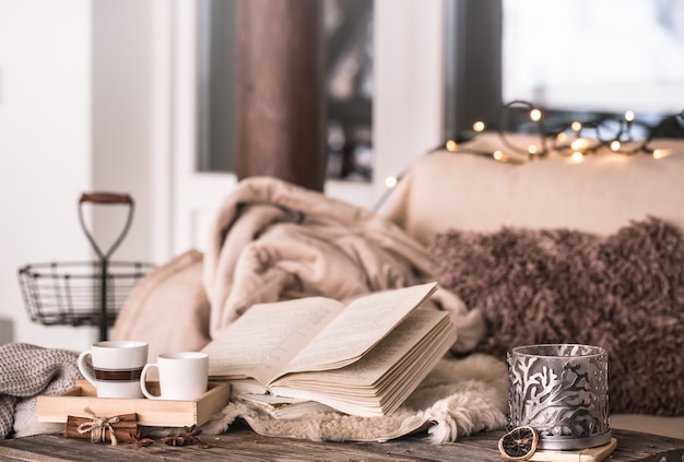 Free photo still life home atmosphere in the interior with cups, a book and candles, on the background of cozy bedspreads