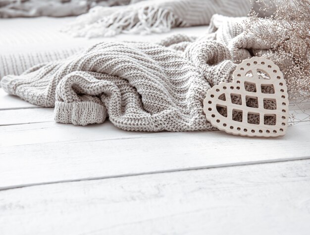 Still life in hygge style with a decorative heart and a knitted element on a wooden surface