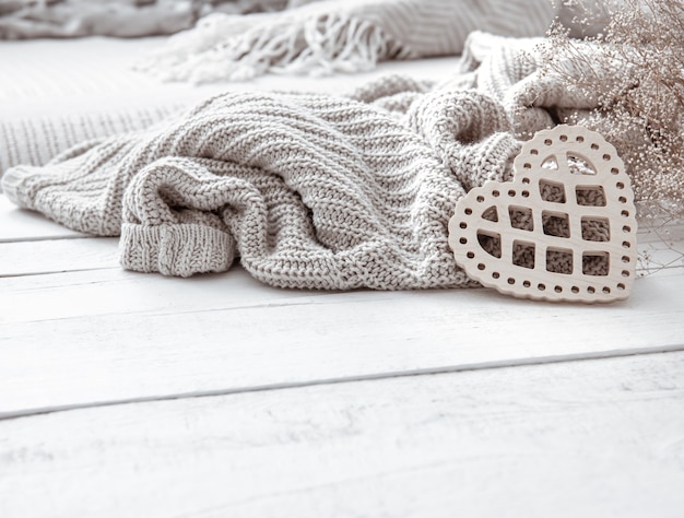 Still life in hygge style with a decorative heart and a knitted element on a wooden surface