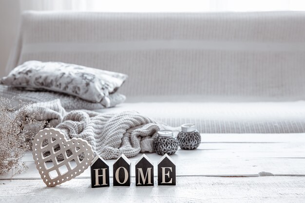 Still life in hygge style with wooden word home, heart and knitted element. The concept of home comfort and modern style.