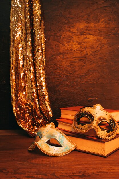 Still life of two venetian carnival mask with books against dark textured background