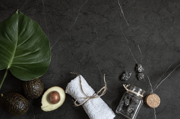 Still life with avocado, towel and stones on a dark marble surface copy space. face and body skin care concept.