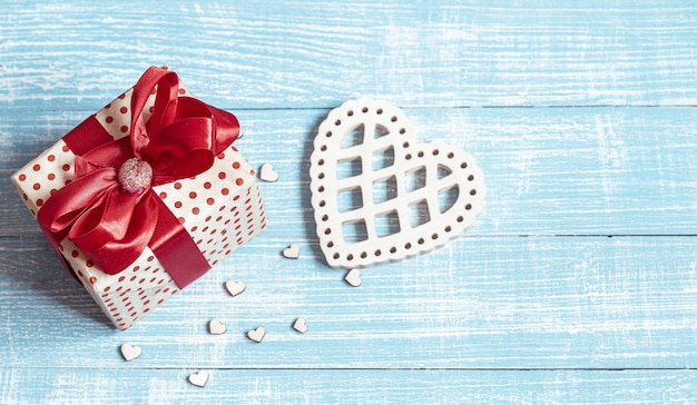 Still life with a beautifully wrapped gift and decorative elements on a wooden surface. Valentine's holiday concept.