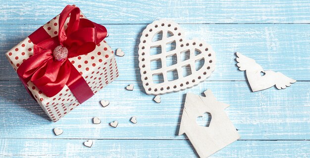 Still life with a beautifully wrapped gift and decorative elements on a wooden surface. Valentine's holiday concept.