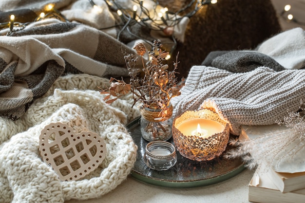 촛대, 장식 세부 사항 및 니트 항목에 촛불이있는 정물. 발렌타인 데이 및 가정 장식의 개념.