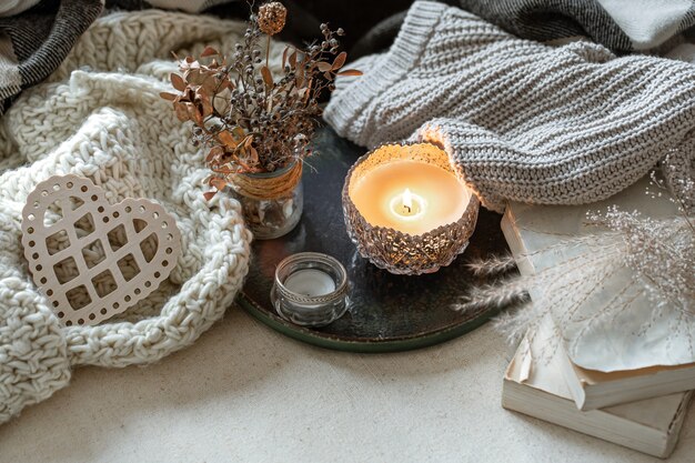 Still life with candles in candlesticks, decor details and knitted items.