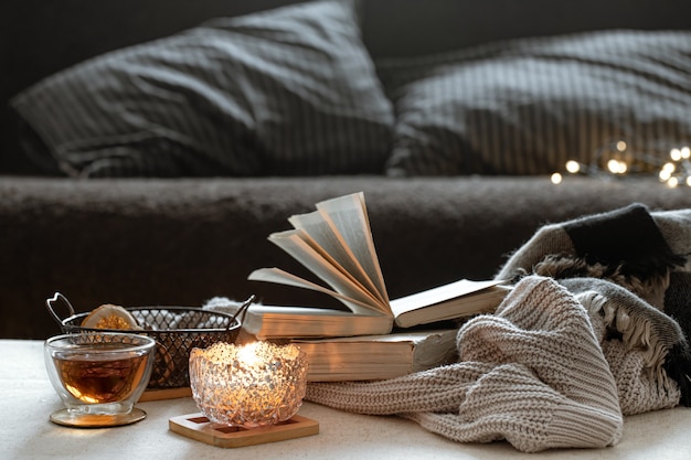 Still life with a cup of tea, books and a burning candle in a beautiful candlestick. Home comfort concept.