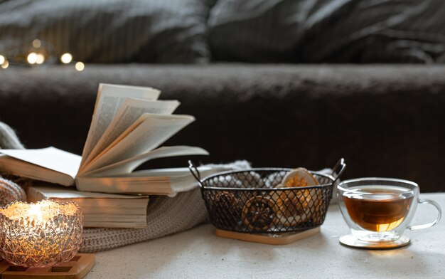 Still life with a cup of tea, books and a burning candle in a beautiful candlestick. Home comfort concept.