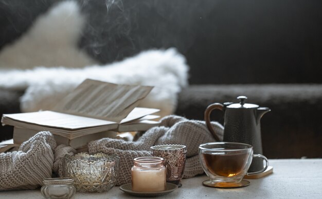 一杯のお茶、ティーポット、本、キャンドル付きの美しいヴィンテージの燭台のある静物。家の装飾の概念。