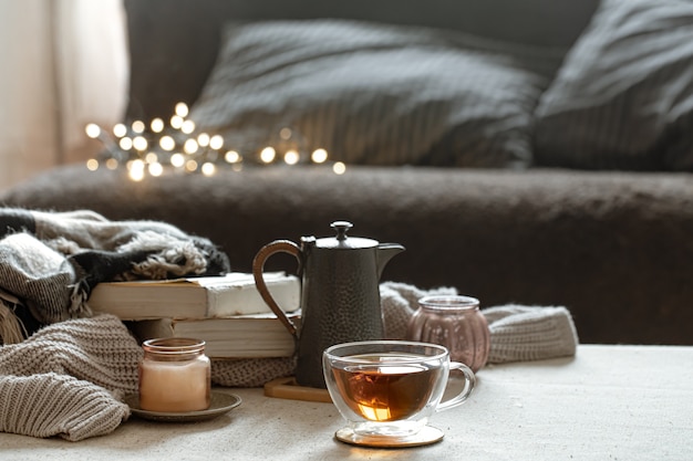 Still life with a cup of tea, a teapot, books and a candle in a candlestick