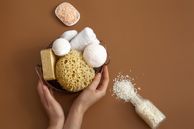 Still life with female hands, bath sponge, bath bombs, soap and white sea salt.