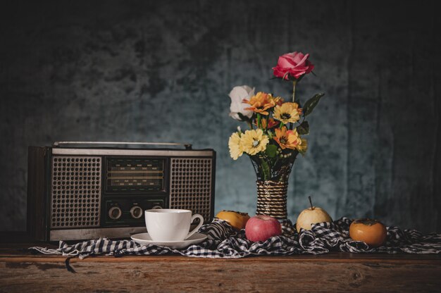 Still life with flower vases with fruits and retro radio