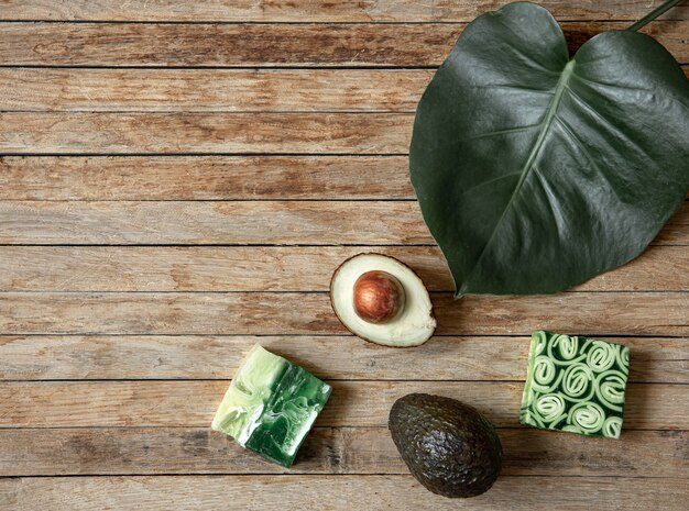 Still life with handmade soap, natural leaf and avocado top view. Organic cosmetics and beauty concept.