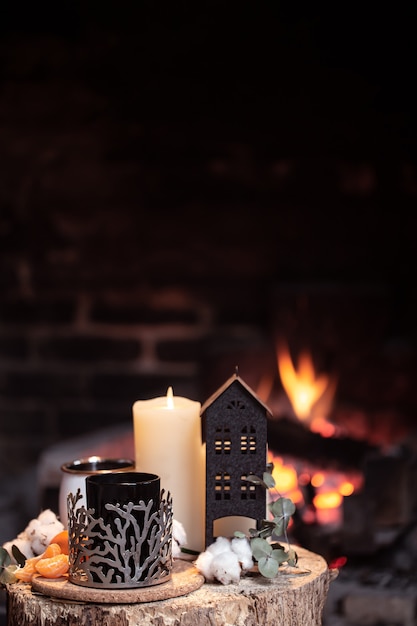 ホットドリンク、キャンドル、燃える火に対する装飾のある静物。暖炉のそばで夜のリラクゼーションのコンセプト。