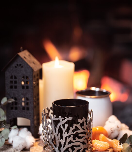 Still life with hot drinks, candle and decor against a burning fire. The concept of an evening relaxation near the fireplace.