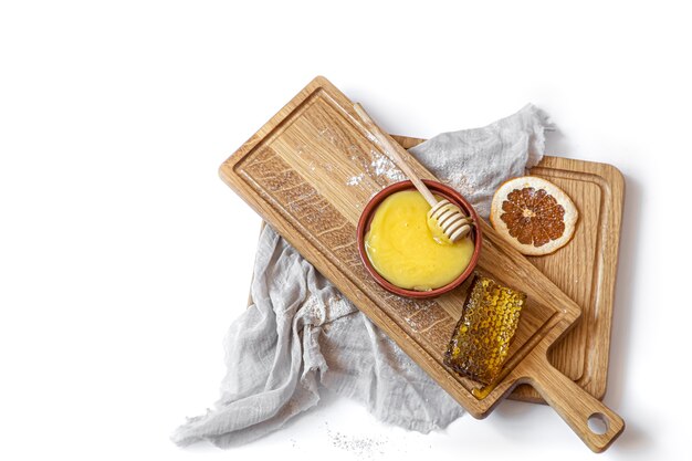 Still life with natural honey and honeycomb on a wooden plank close up isolated.