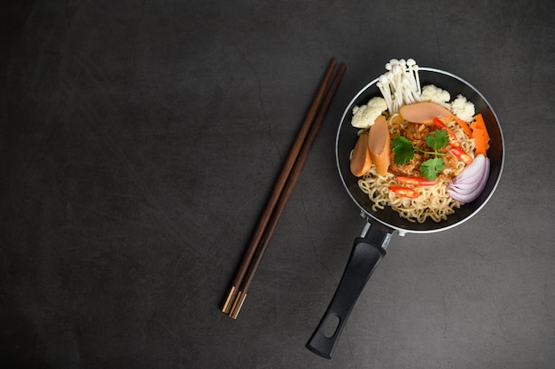 Foto gratuita natura morta con noodles in padella e bacchette.