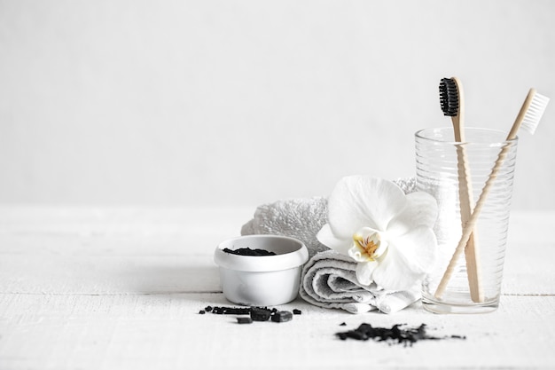 Free photo still life with organic bamboo brushes and activated carbon powder and an orchid flower as a decorative element. oral hygiene and dental care.