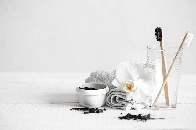 Still life with organic bamboo brushes and activated carbon powder and an orchid flower as a decorative element. Oral hygiene and dental care.
