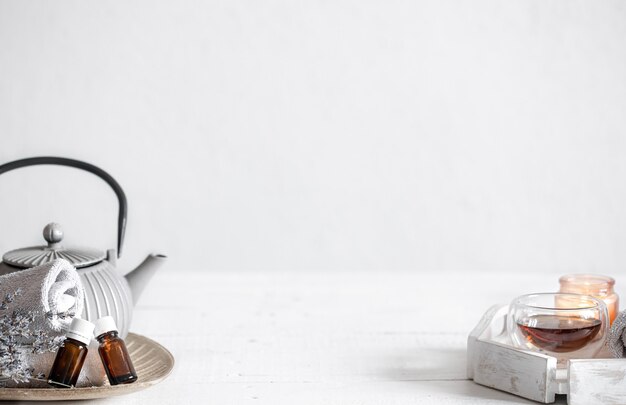 Натюрморт с чайником, чаем, бутылками с маслом и веточками лаванды. Фон концепции ароматерапии и здравоохранения