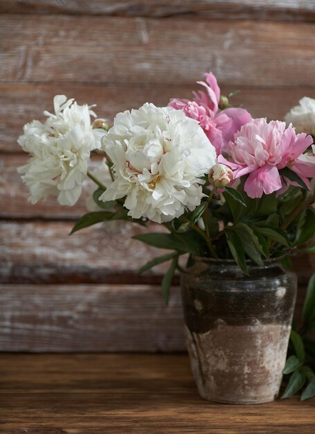 木製の背景に古いセラミック花瓶に白とピンクの牡丹と静物 Premium写真