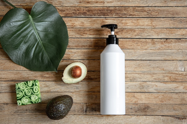 Free photo still life with white mock-up bottle with dispenser, natural soap and avocado. organic cosmetics and beauty concept.