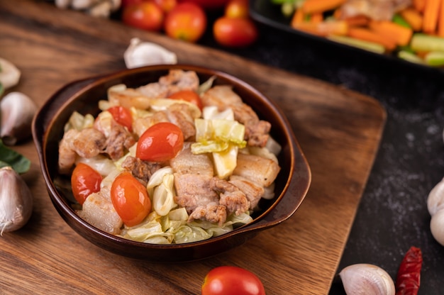 Stir cabbage with pork belly in a plate on a wooden plate.