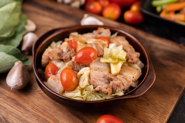 Stir cabbage with pork belly in a plate on a wooden plate.