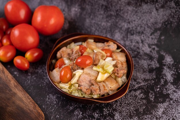 Stir cabbage with pork belly in a plate on a wooden plate.